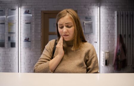 女性用手按著臉頰，表情不適，牙齦或口腔疼痛的情境