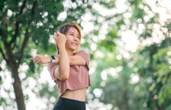 女性在戶外伸展手臂，舒緩運動後的上肢與肩膀痠痛