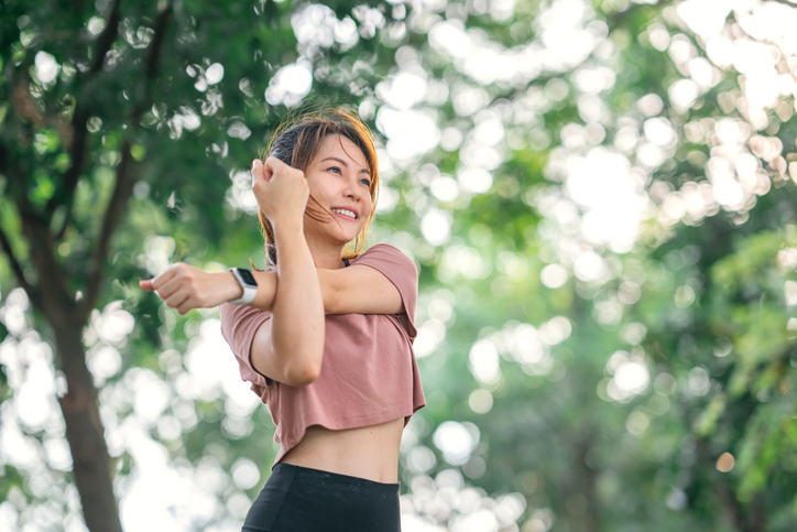 女性在戶外伸展手臂，舒緩運動後的上肢與肩膀痠痛