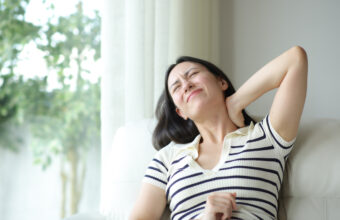 女性因落枕皺眉，用手扶著頸部側邊