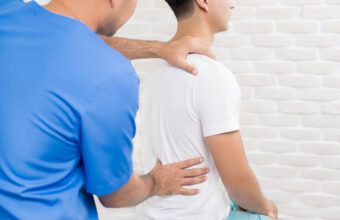 穿藍色刷手服的治療師為患者檢查下背與腰椎