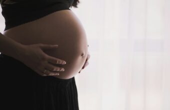 孕婦以雙手托住隆起腹部的側面特寫